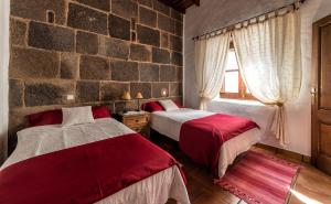a bedroom with two beds and a stone wall at Casa Gaida in Tías