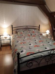 ein Bett mit einer Bettdecke und Blumen darauf in der Unterkunft Les Roses Trémières in Trans