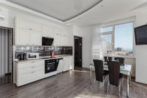 a kitchen with white cabinets and a table with chairs at Odessa Pearl Apartments in Odesa