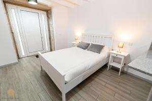 a white bedroom with a white bed and two tables at Casa do Foral in Ponte de Lima