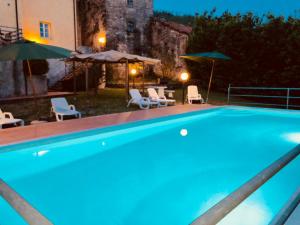 een groot zwembad met stoelen en parasols bij La vecchia canonica in Fivizzano