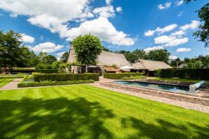 a garden with a lawn and a swimming pool at Hoeve de Eshof in Norg