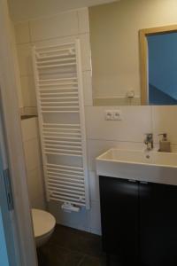 ein Badezimmer mit einem Waschbecken, einem WC und einem Spiegel in der Unterkunft Ferienzimmer Segeberg in Bad Segeberg