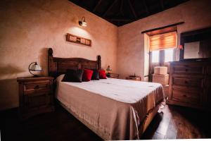 Un dormitorio con una cama con almohadas rojas y una ventana en Casa Elena, en Tijarafe