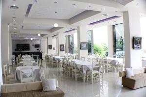 a restaurant with white tables and chairs and windows at Hotel Blue Days in Borsh