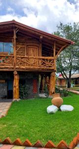a wooden building with a roof on the grass at Zaysant Ecolodge in Puembo