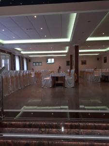 um salão de banquetes com mesas e cadeiras brancas em Business Club Selenča em Bač