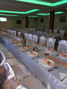 uma mesa longa com cadeiras brancas e pratos de comida em Business Club Selenča em Bač