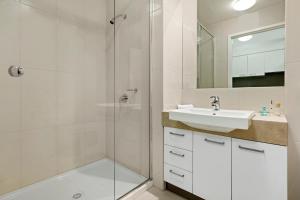 a bathroom with a shower, sink, and mirror at Quest Moorabbin in Moorabbin