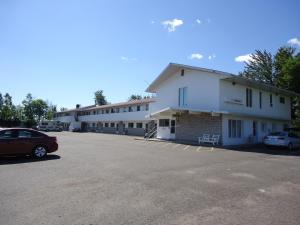 un bâtiment avec des voitures garées dans un parking dans l'établissement Voyageur Motel, à Thunder Bay