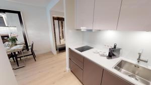 a white kitchen with a sink and a table at White Pearl Apartment 1.15 in Timmendorfer Strand