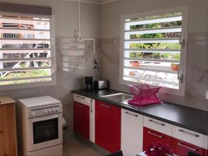 una cocina con armarios rojos y blancos y fregadero en Bikamado, en Deshaies
