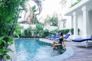 a woman sitting next to a swimming pool in a hotel at Umalas Suites in Seminyak