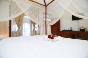 a white bed with a flower on top of it at Toba Village Inn in Tuk Tuk