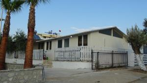 a white house with a gate and palm trees at Seaside Cabin Ksamil in Ksamil