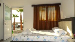 een slaapkamer met een bed en een raam met palmbomen bij Seaside Cabin Ksamil in Ksamil