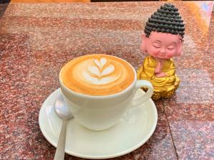 a cup of coffee sitting on a table next to a statue at AMIGO LEH Guesthouse in Leh