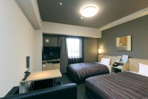 a hotel room with two beds and a desk at Hotel Route-Inn Shimizu Inter in Shizuoka