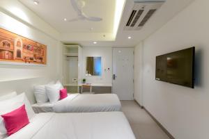 two beds in a room with a flat screen tv at Hotel Centro in Pune