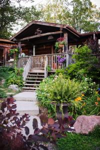 a log cabin with a porch and flowers in front of it at Shambhala Bed and Breakfast in Buckhorn
