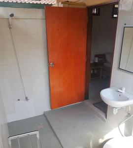 a bathroom with a wooden door and a sink at Secret Garden Bungalows in Nusa Lembongan