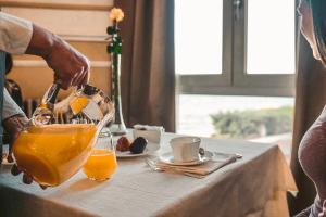 a person pouring orange juice into a glass on a table at Villa Mosca Charming House in Alghero