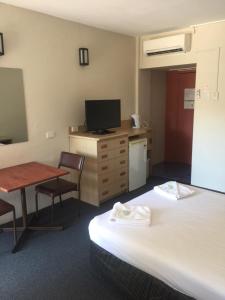 a hotel room with a bed, table and television at Darwin Poinciana Inn in Darwin