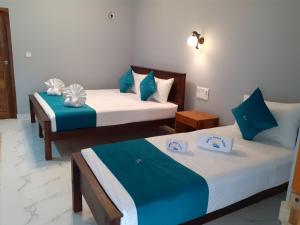 2 camas en una habitación de color azul y blanco en MRD Beach Hotel, en Trincomalee