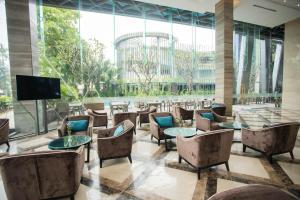 a lobby with tables and chairs and a large window at The Mira Central Park Hotel in Bien Hoa