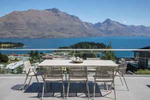 a table and chairs on a balcony with a view of a lake at Papillon, a Relax it's Done luxury holiday home in Queenstown