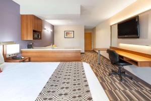 ロビンソン・タウンシップにあるMicrotel Inn & Suites by Wyndham Pittsburgh Airportのベッドとデスクが備わるホテルルームです。