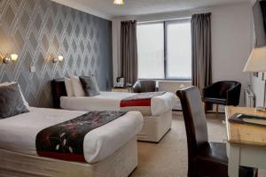 a hotel room with two beds and a desk at Best Western Princes Marine Hotel in Brighton & Hove