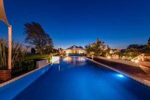 a swimming pool in front of a house at night at Ramada Resort By Wyndham Rotorua Marama in Rotorua