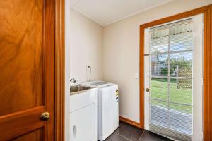 een wasruimte met een wasmachine en een raam bij Quality Suites Huka Falls in Taupo
