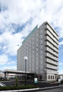 a large white building with a sign on it at Hotel Route-Inn Niigata Nishi Inter in Niigata