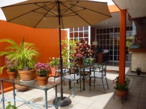 a patio with a table with plants and an umbrella at Hotel Camba in Oaxaca City