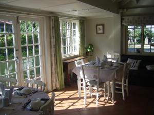 a dining room with a table and chairs and windows at Nutmeg Guest House in Howick