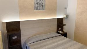 ein kleines Schlafzimmer mit einem Bett mit einer Lampe darüber in der Unterkunft Albergo Gilda in Caldonazzo