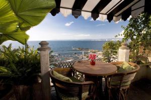 een tafel en stoelen op een balkon met uitzicht op de oceaan bij Quinta Maria Cortez in Puerto Vallarta