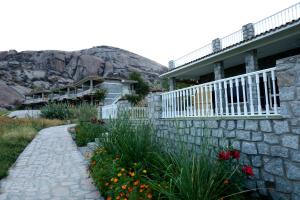 a house with a stone wall and flowers in front at Amritara Jawai Resort in Pāli