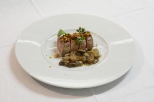 un plato blanco con un trozo de carne y setas en Albergo Morandi en Valbondione