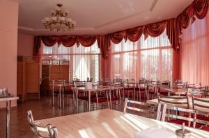 a dining room with tables and chairs and large windows at Zlata Inn in Tamchy