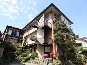 un edificio con balcones y un jardín frente a él en Besshoonsen Nanjyo Ryokan en Ueda