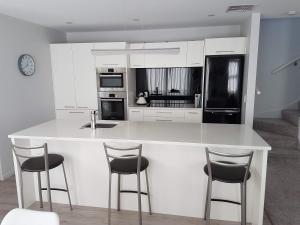 a kitchen with a white counter and three bar stools at Delightful Petone Townhouse in Lower Hutt