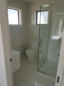 a bathroom with a toilet and a glass shower at Delightful Petone Townhouse in Lower Hutt