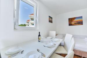 a white dining room with a white table and a window at Royal Apartments in Novalja