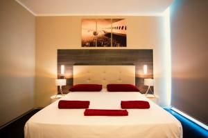 a bedroom with a large white bed with two red pillows at Star Hotel Airport Verona in Dossobuono