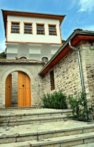 a house with two wooden doors and some stairs at Argyropolis Boutique Hotel in Gjirokastër