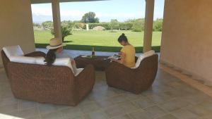 dwie kobiety siedzące w wiklinowych krzesłach na patio w obiekcie Agriturismo Sa Ruda w mieście Cabras