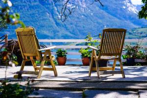 2 sillas sentadas en un patio con montañas al fondo en Fjord House, en Grimo